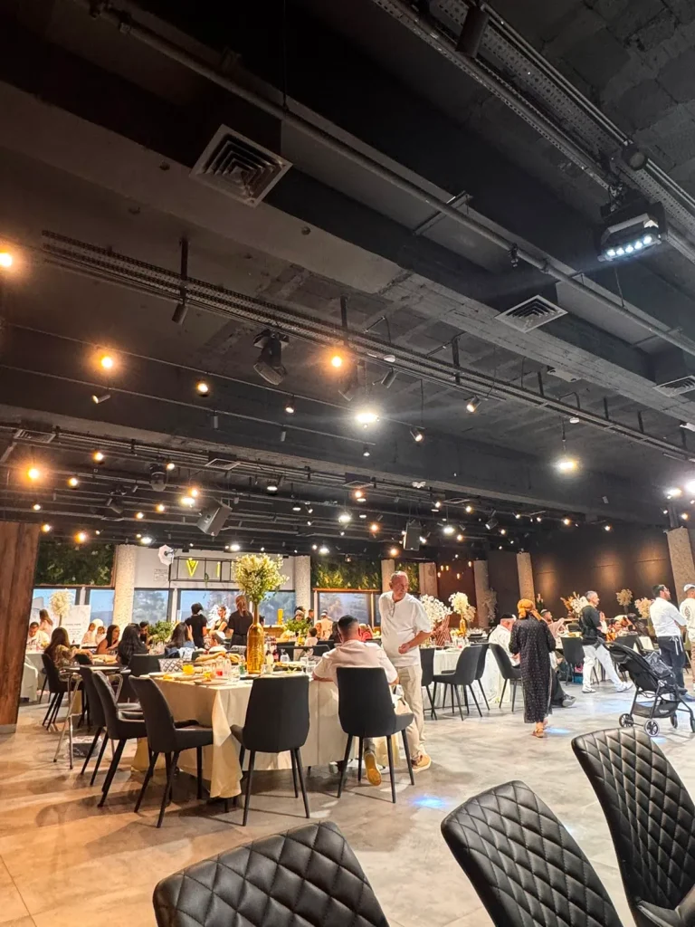 אורחים סביב שולחנות עגולים ערוכים באירוע באולם Vine